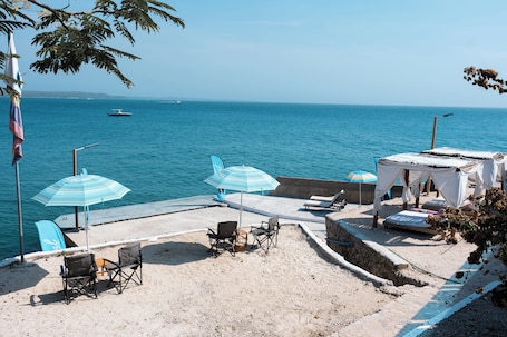 A beachside patio with chairs, umbrellas, and a small tented area overlooking the sea.. Hotel Isla Real