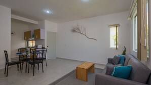 Una sala de estar moderna con un sofá gris, una mesa de centro de madera y un comedor con una mesa y sillas.