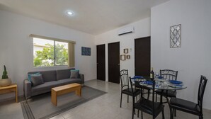 Una sala de estar moderna con un sofá, una mesa de centro y un comedor con sillas y una mesa.