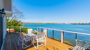 Una terrazza in legno con tavolo e sedie, affacciata su un corpo d'acqua.