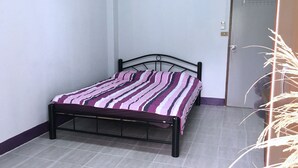 A small, single-bed room with a metal frame, a striped bedspread, and a tiled floor. - TC Mansion (Nonthaburi)