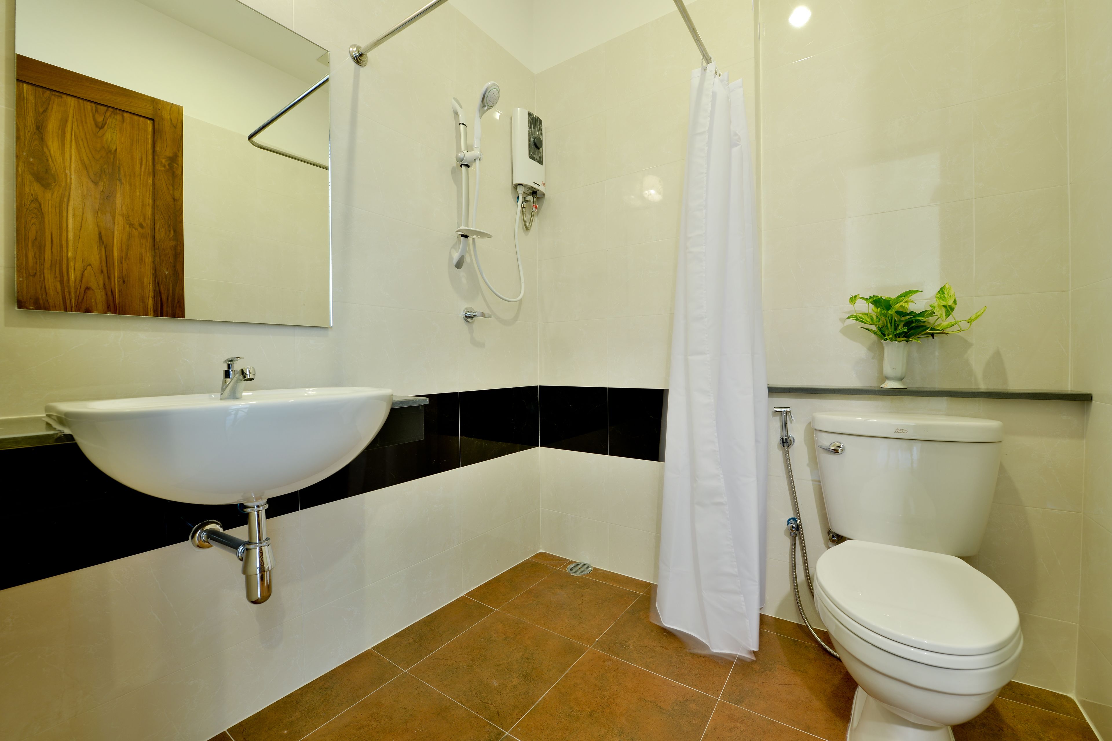 Baño con lavamanos, inodoro, ducha y espejo.