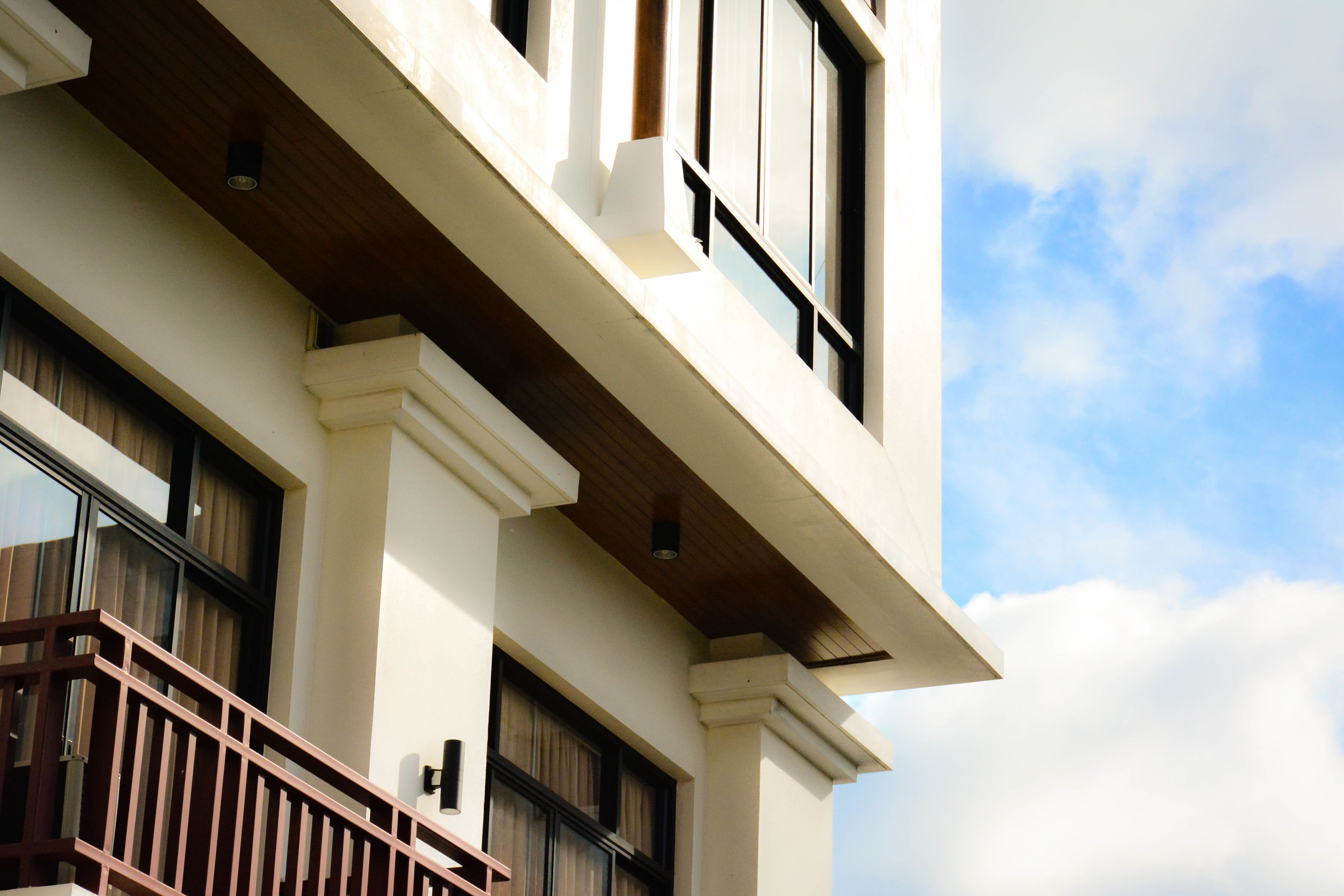 A multi-story building with a balcony, large windows, and a clear sky.