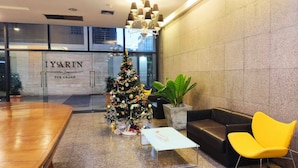Un vestíbulo con un árbol de Navidad, un mostrador de recepción y una zona de estar con una silla amarilla.