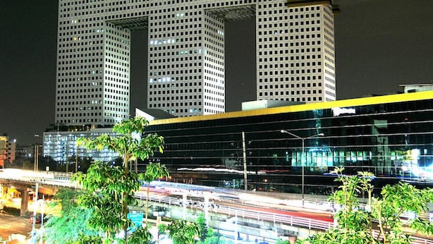 Un edificio moderno de gran altura con fachada enrejada y una sección angular destacada.