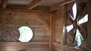 Ein Holzblockbau-Innenraum mit schrägverlaufender Decke, einem Rundfenster und einem großen Fenster mit sternförmigem Design.