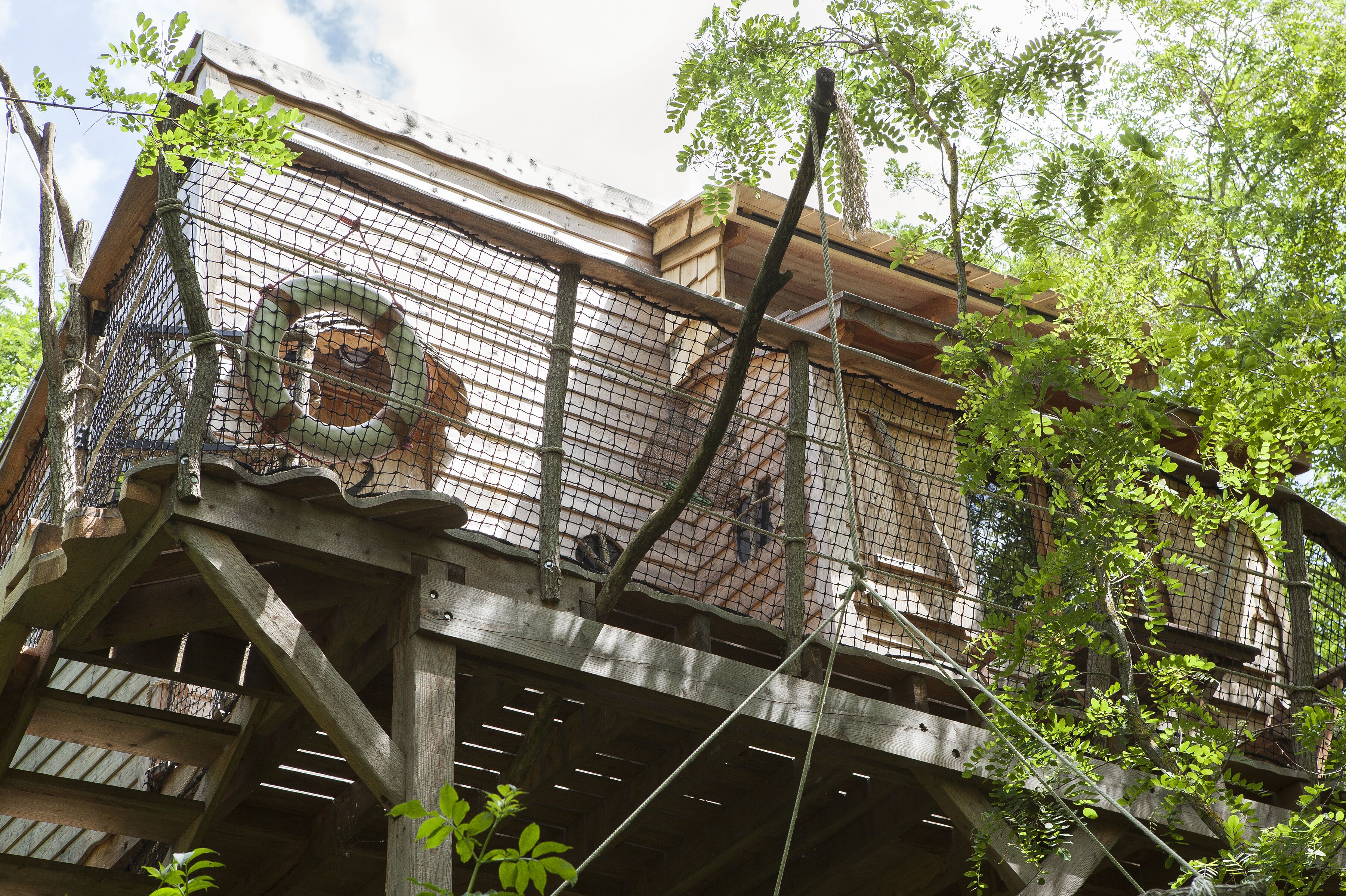 Eine Holzhütte mit einem Netzgehege, möglicherweise ein Vogelhaus oder ein Vogelvolier, umgeben von Bäumen.