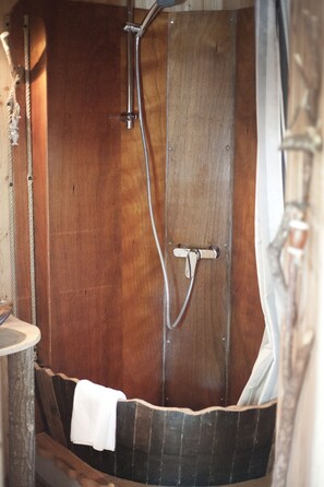 Una bañera de madera con ducha y grifo.
