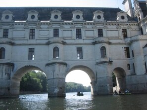 Un edificio histórico con un gran arco sobre un río, que presenta arquitectura clásica con múltiples ventanas y detalles decorativos.