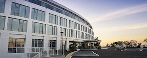 A modern building with a curved facade, large windows, and a parking lot. - Potalaka Naksan Beach Wellness (Yangyang)