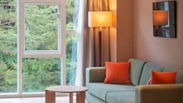 A room with a sofa, a small round table, and a window with curtains.