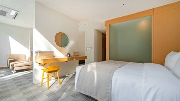 A modern hotel room with a bed, a desk, a chair, and a large mirror.