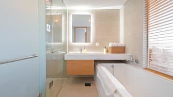 Un bagno moderno con cabina doccia in vetro, mobile lavabo in legno, vasca da bagno e finestra con persiane.