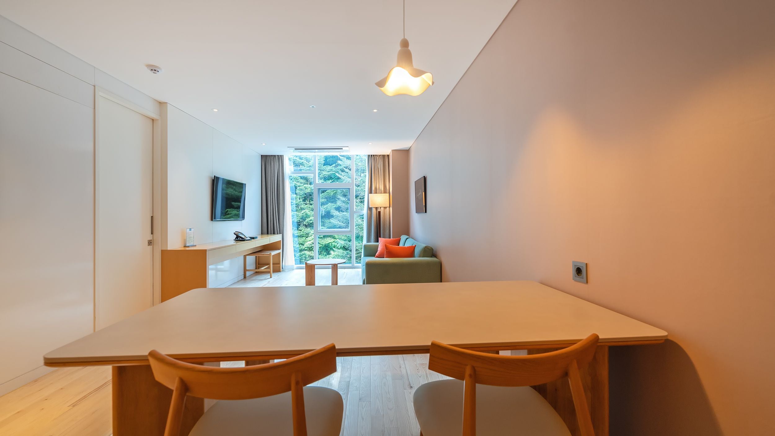 Un interior moderno con zona de comedor, sofá y televisor montado en la pared.