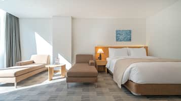 Una habitación de hotel con cama, sofá, sillón, mesita de noche y lámpara.