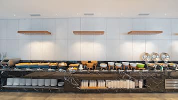 Montaje de bufé con diferentes alimentos, tazones y platos dispuestos en una barra.