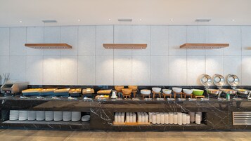 Un buffet avec différents plats, des bols et des assiettes disposés sur un comptoir.