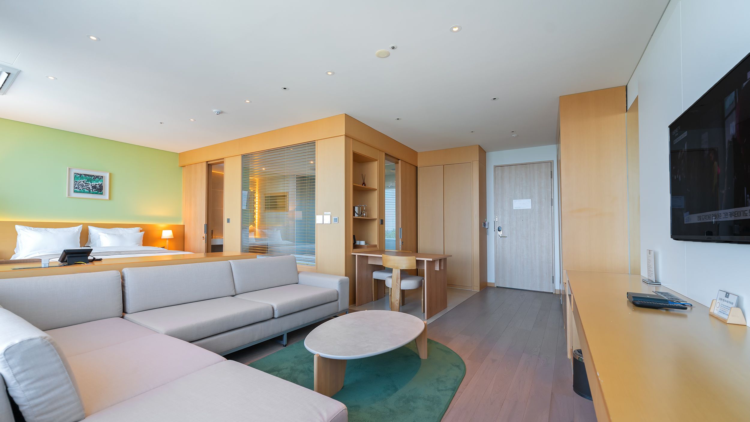 Une chambre d’hôtel moderne équipée d’un canapé, d’une table à manger et d’un téléviseur fixé au mur.