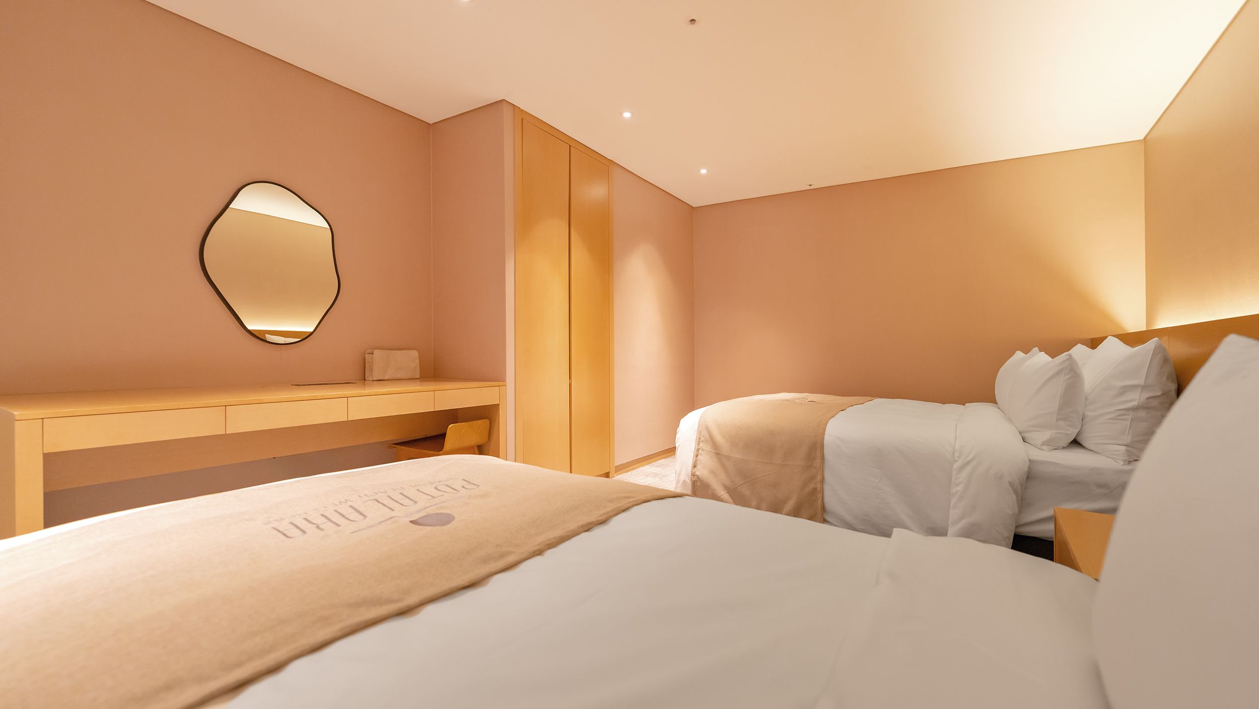 Una habitación de hotel con una cama, una mesita de noche, un espejo y un armario.