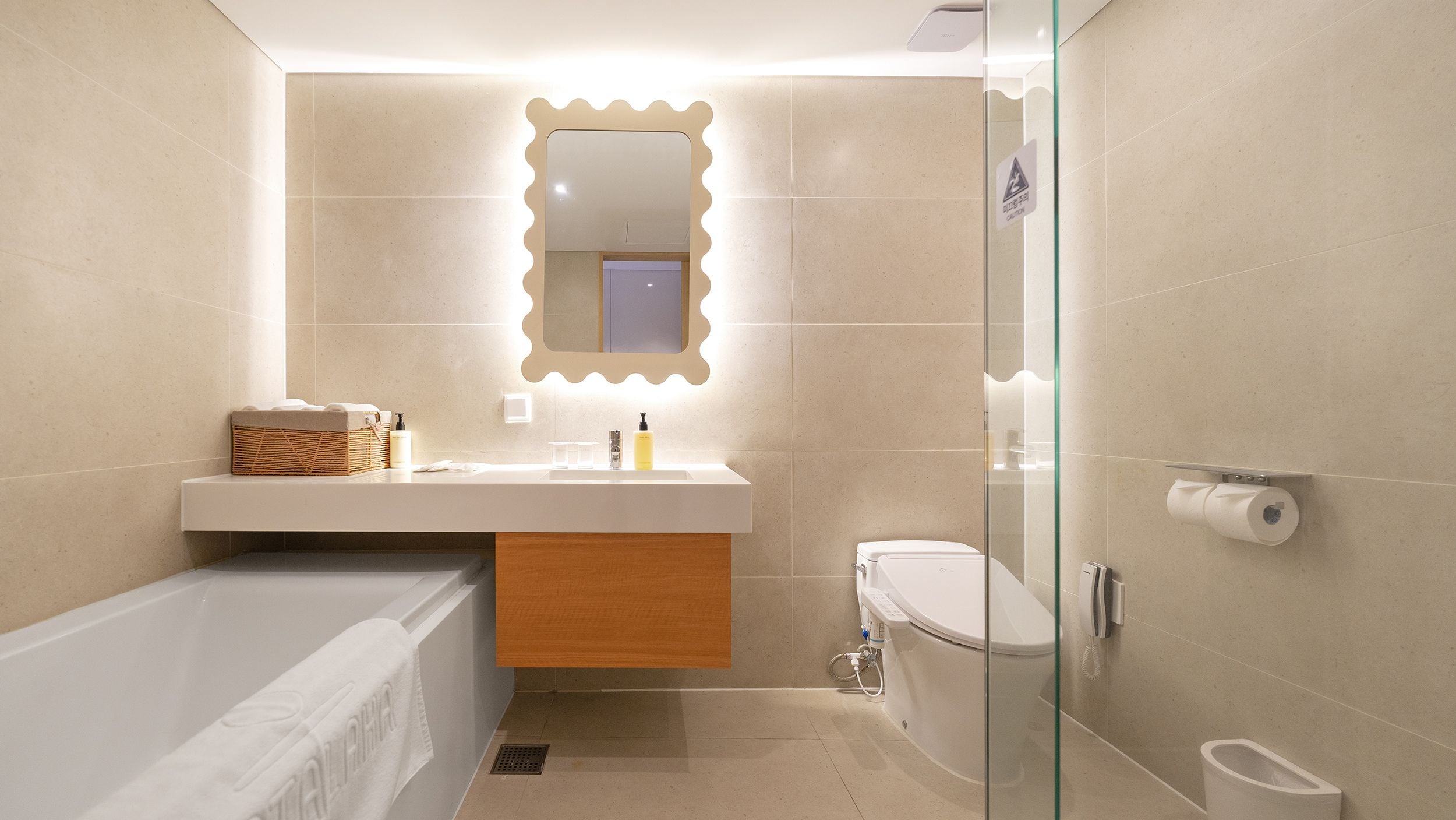 A modern bathroom with a bathtub, a vanity with a mirror, a toilet, and a glass shower enclosure.