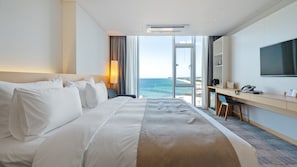 A hotel room with a bed, a desk, a TV, and a view of the sea. - Potalaka Naksan Beach Wellness (Yangyang)