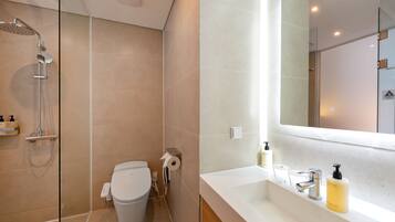 A modern bathroom with a shower, toilet, and a large mirror above the sink.