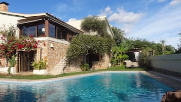 Relax by the serene pool surrounded by lush greenery and flowering plants.
