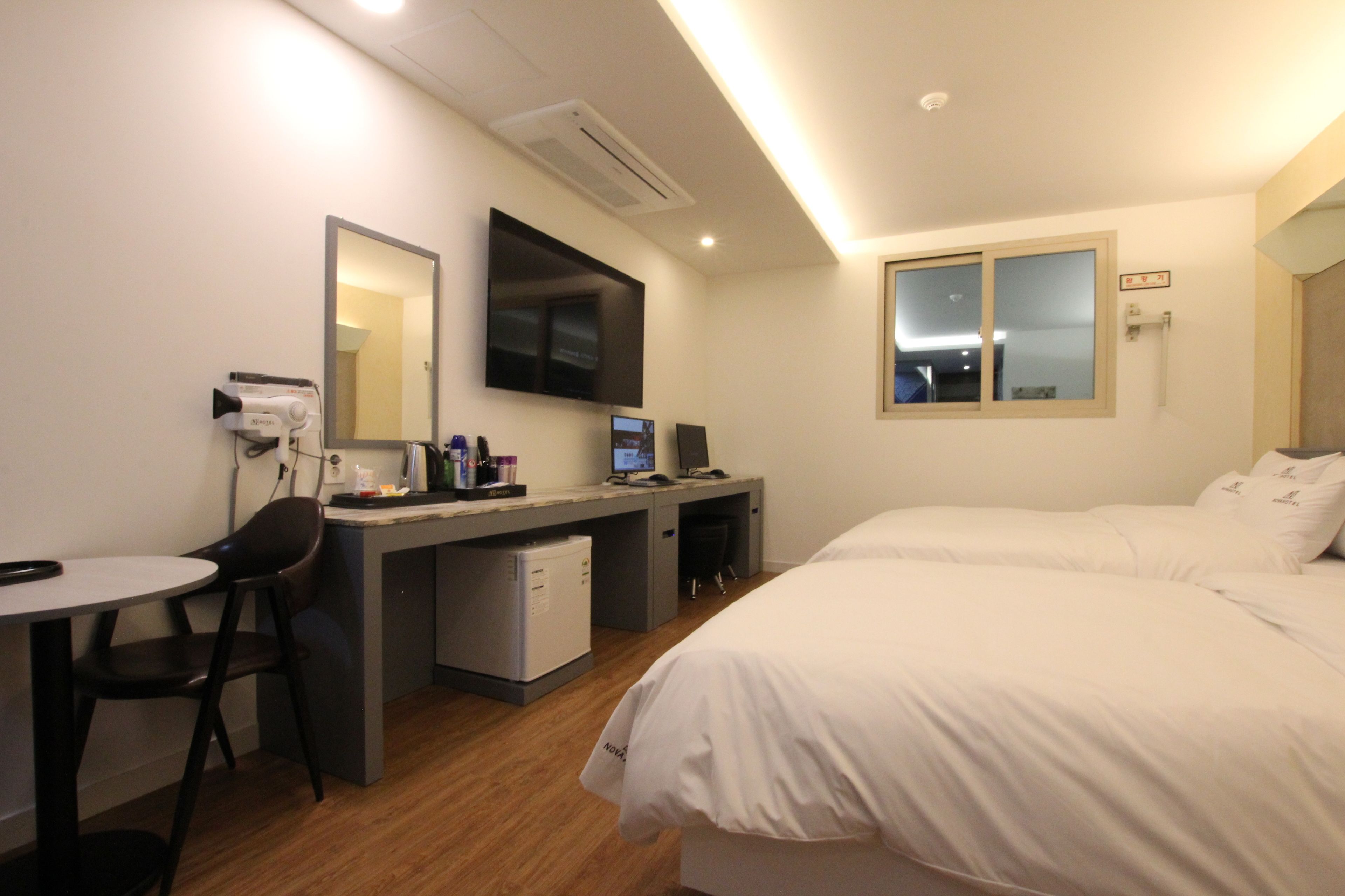 Une chambre d’hôtel comprenant un lit, un bureau avec un ordinateur, une chaise et un petit réfrigérateur.