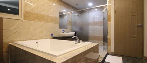 A modern bathroom with a large bathtub, a sink, and a mirror.