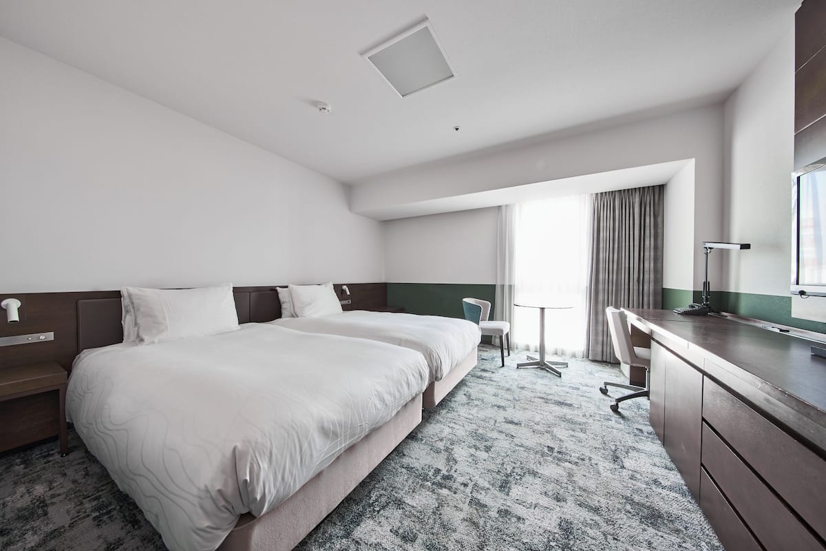 A hotel room with a large bed, a desk, and a chair.