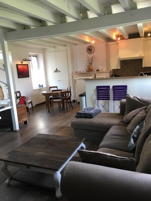 A modern living room with a sofa, a wooden coffee table, and a dining area with chairs and a table.