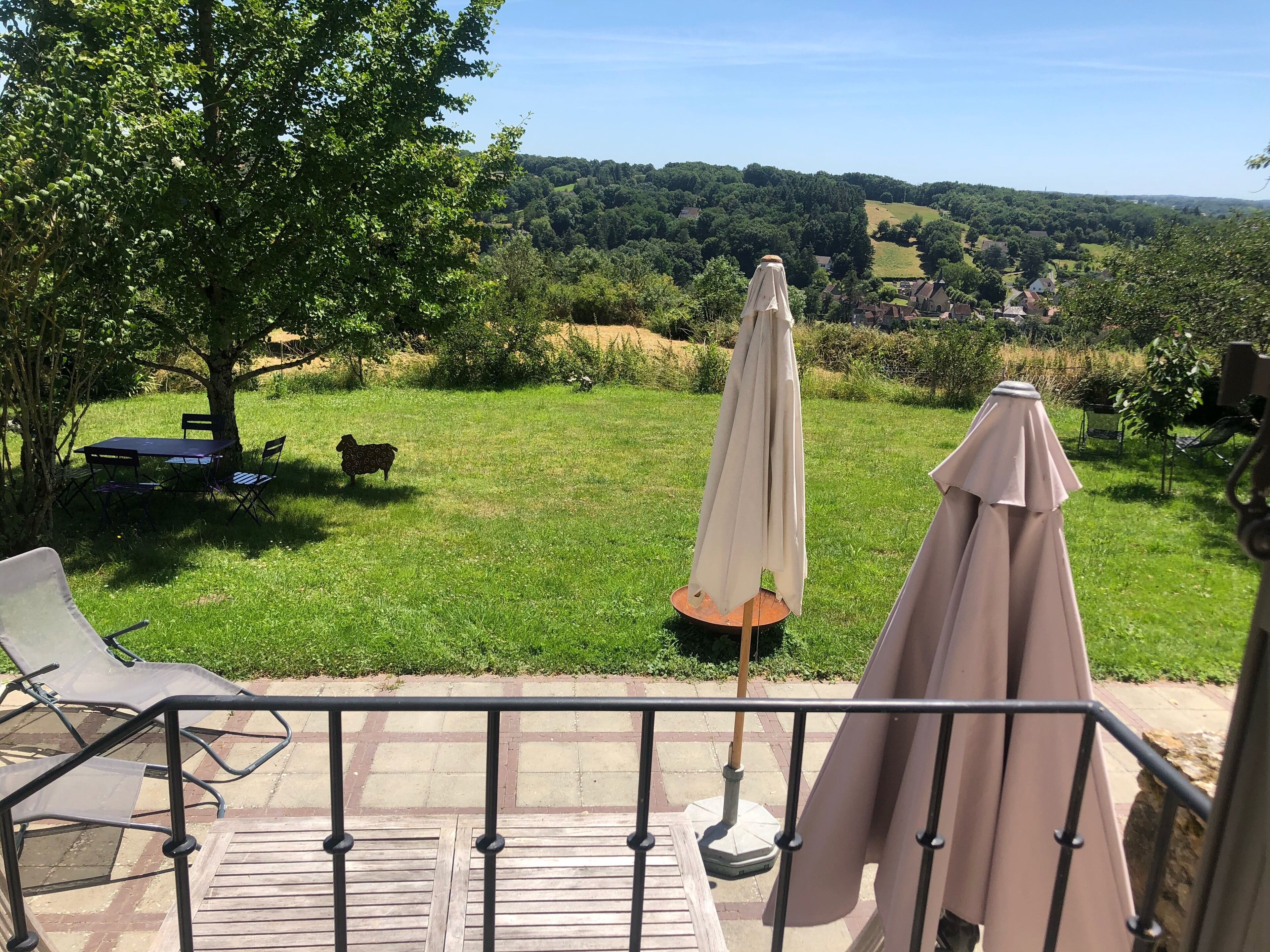 Une terrasse aménagée avec du mobilier d’extérieur, comprenant une table et des chaises, ainsi que deux parasols.
