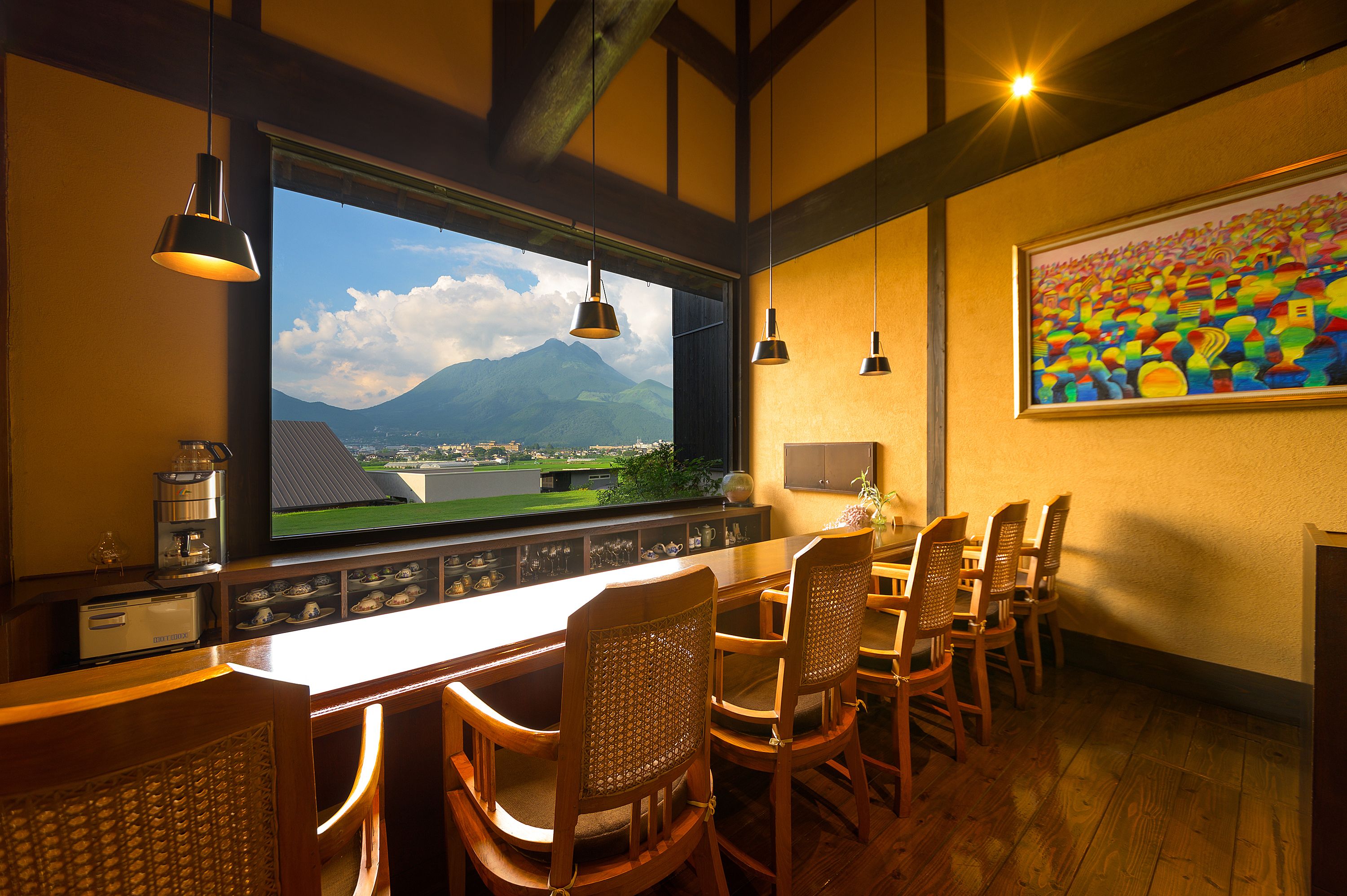 A bar area with a large TV screen, wooden chairs, and a painting on the wall.