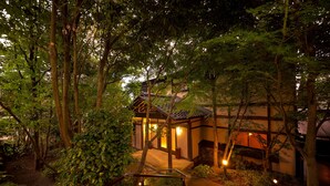 A traditional Japanese-style building surrounded by dense foliage. - Yufuin Onsen Toshoan (Yufu)