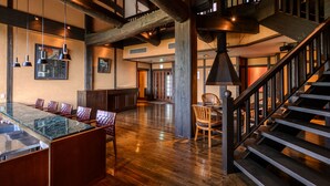 A spacious interior with a wooden staircase, a glass-top dining table, and a conference room area. - Yufuin Onsen Toshoan (Yufu)