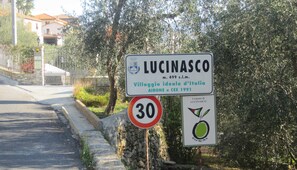 A street sign for Lucinasco, a village ideal for Italy, with a speed limit sign of 30.