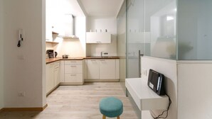 Una cocina moderna con armarios blancos, encimera de madera y un taburete color turquesa.