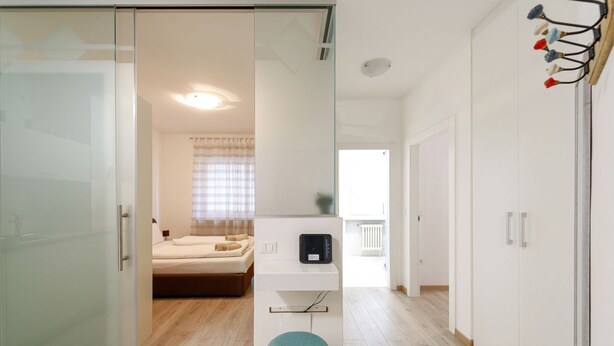Un dormitorio moderno con puerta de cristal, cama, escritorio y armario.