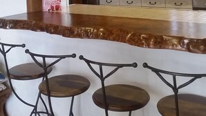 A kitchen with a bar area, wooden beams, white cabinets, and a sign that reads "Gathering Place." - Rural peaceful house close to beach, golf and  shops. House sleeps 7/9.  (Grezac)