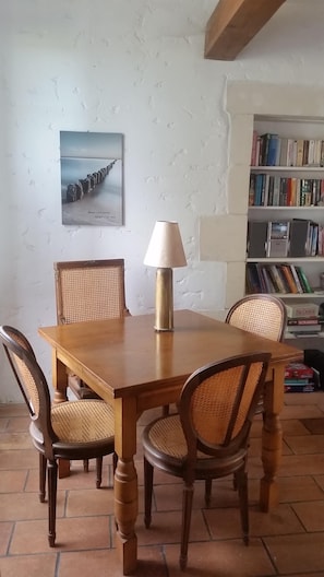 Une table à manger avec quatre chaises, une lampe, une bibliothèque et un tableau encadré au mur.