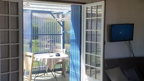A room with a sliding glass door leading to an outdoor patio area with a table and chairs. - Rural peaceful house close to beach, golf and  shops. House sleeps 7/9.  (Grezac)