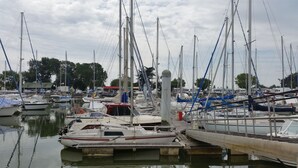 A marina with multiple boats docked, a wooden pier, and a building with a red roof in the background. - Rural peaceful house close to beach, golf and  shops. House sleeps 7/9.  (Grezac)