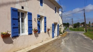 A building with blue shutters and potted plants on the windowsills. - Rural peaceful house close to beach, golf and  shops. House sleeps 7/9.  (Grezac)