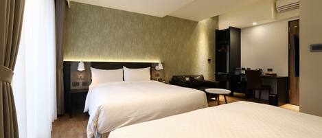 A hotel room with two beds, a desk, a chair, a small table, and a mirror.
