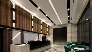 Un espace d’accueil moderne avec un comptoir de réception en marbre, des panneaux muraux en bois et des fauteuils à revêtement vert.