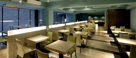Un restaurant moderne avec des tables et des chaises hautes, de grandes fenêtres et une vue sur le paysage urbain.