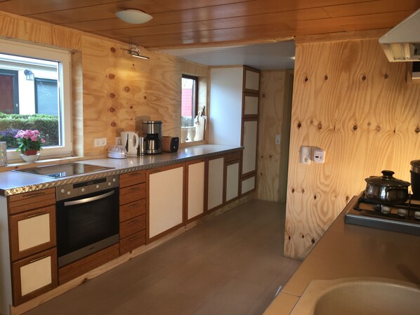 A modern kitchen with wooden cabinetry, a built-in oven, and a sink.