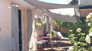 A patio with a table and chairs, a white door, and a white chair. - Charming mazet for 4 pers. 33m2 swimming pool (Saint-Paul-De-Vence)