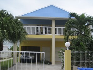 A two-story building with a blue roof, a balcony on the upper floor, and a gated entrance.