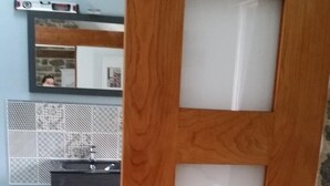 A wooden door with frosted glass panels, a bathroom with a sink and mirror, and a tiled floor. - Family room, 2 mins from the beach (Plouër-Sur-Rance)